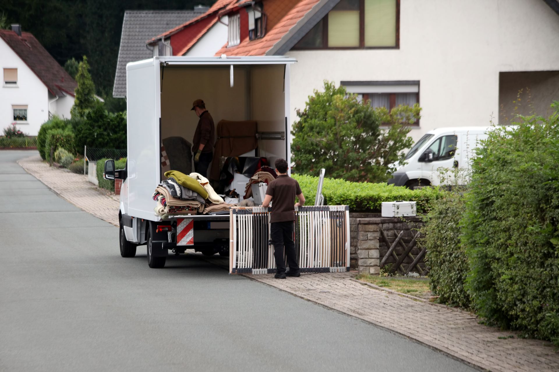 Möbel und Gegenstände werden in einen Transporter geladen – Entrümpelung in einer Wohngegend.