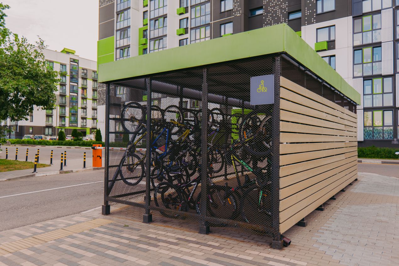 Fahrradgarage aus Holz und Metall mit Gitternetz vor moderner Wohnanlage im Stadtgebiet